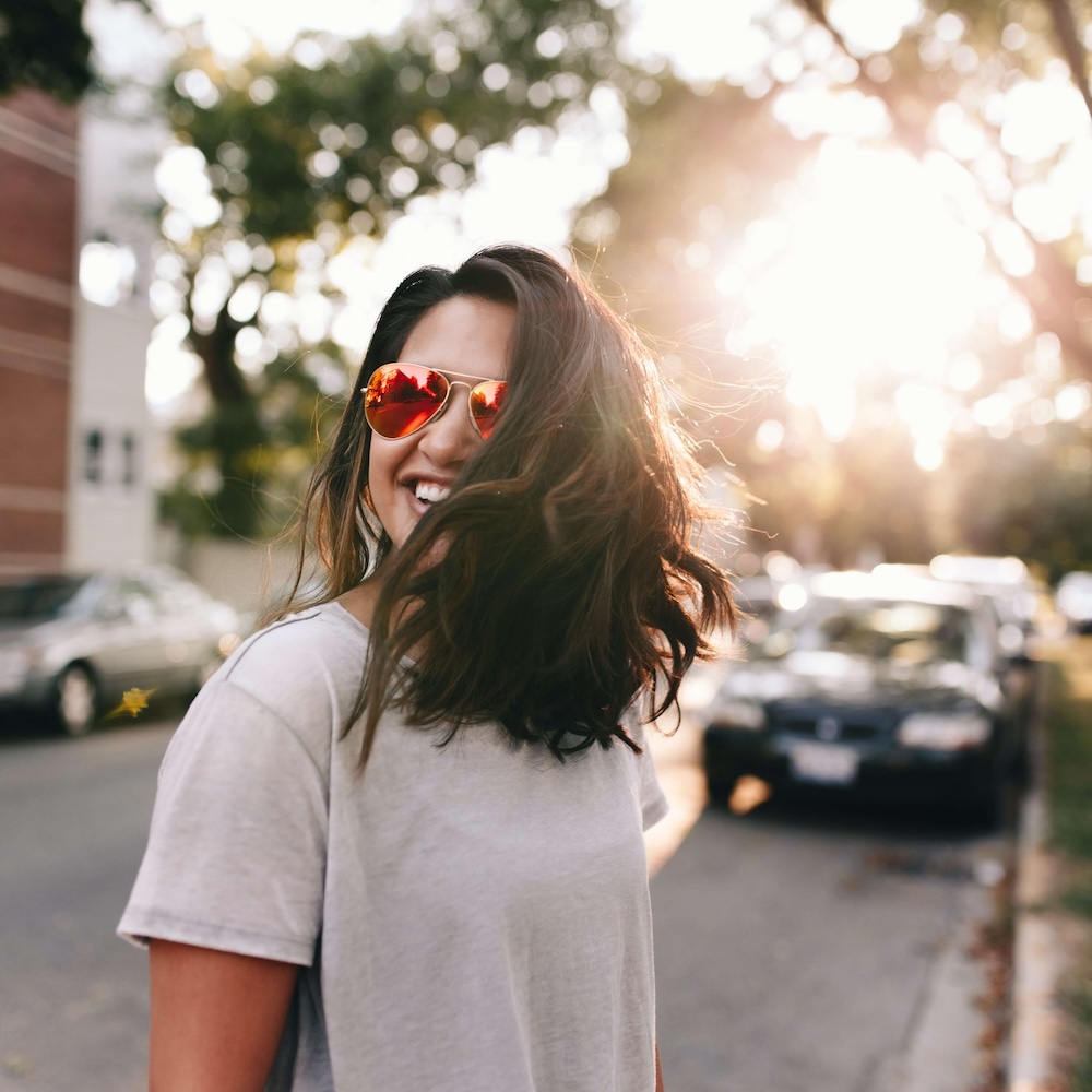Image of a smiling woman wearing sunglasses standing outside. Discover how an EMDR therapist in Las Vegas, NV can help you work through your DID symptoms in healthy ways.