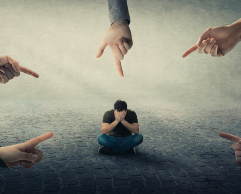 A group of hands point surrounding a person sitting on the ground and covering their face. Learn how an EMDR therapist in Las Vegas, NV can offer support with addressing social anxiety. Learn more about EMDR in Las Vegas, NV by searching for emdr therapy for anxiety in Las Vegas, NV