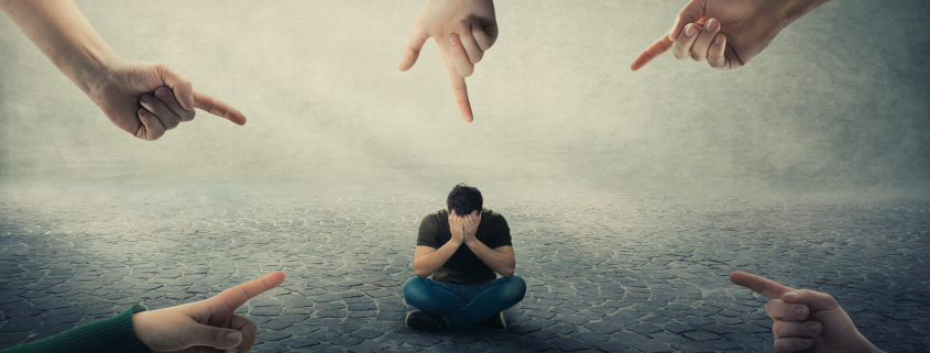 A group of hands point surrounding a person sitting on the ground and covering their face. Learn how an EMDR therapist in Las Vegas, NV can offer support with addressing social anxiety. Learn more about EMDR in Las Vegas, NV by searching for emdr therapy for anxiety in Las Vegas, NV