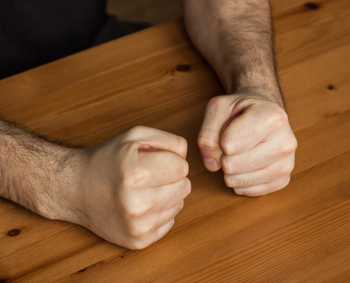 A close up of balled fists on a table. Learn how a DBT therapist in Torrance, CA can offer support by searching for online DBT therapy and other forms of support. Search for DBT therapy in Las Vegas to learn more.